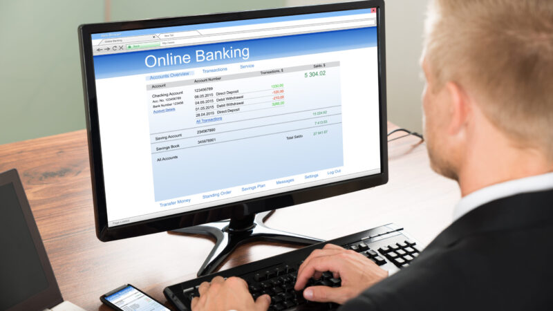 Close-up Of A Businessman Using Online Banking Service On Computer At Office
